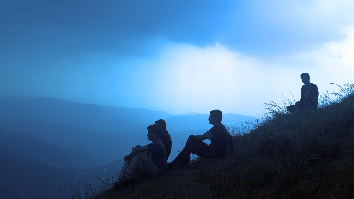mężczyźni siedzący na wzgórzu